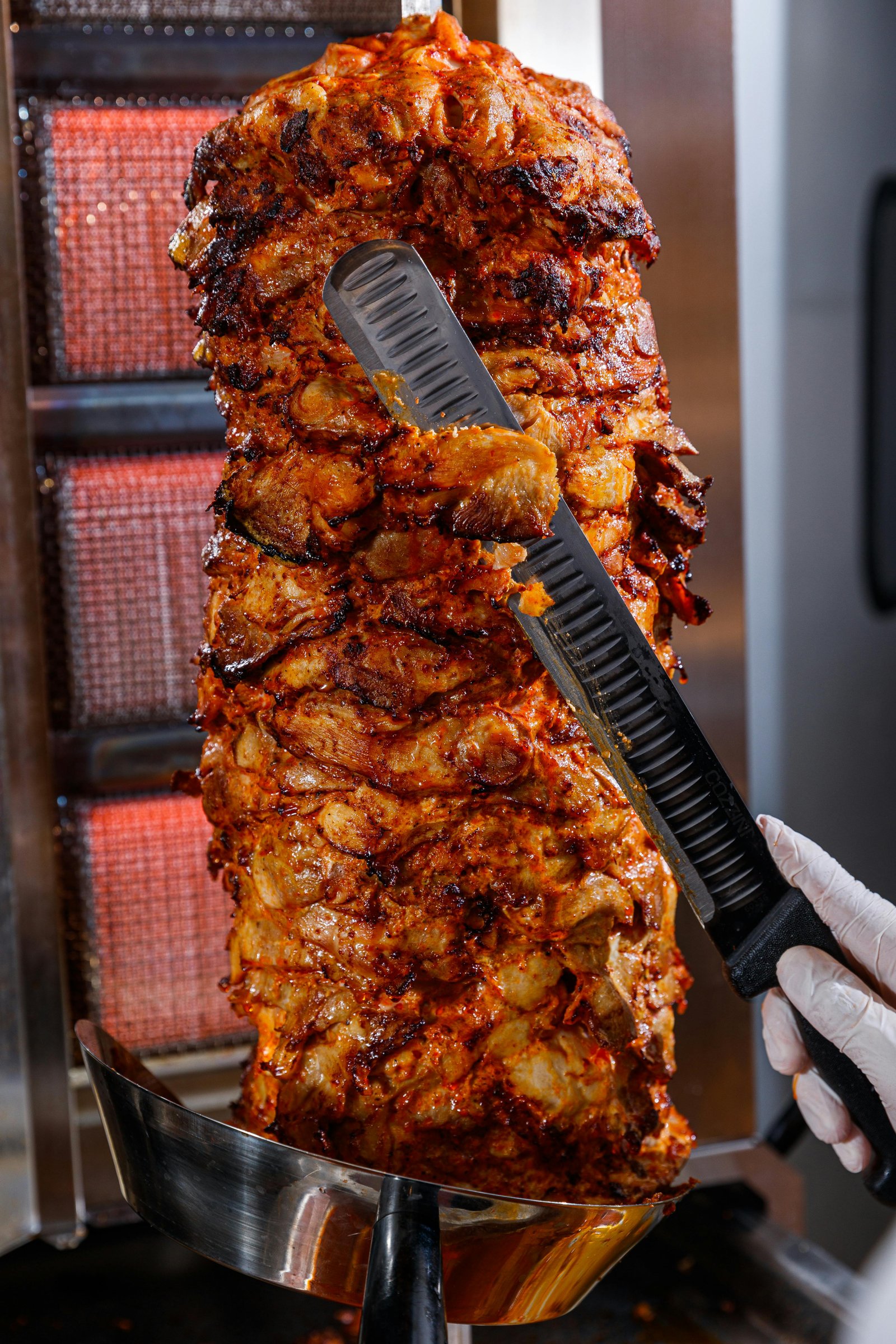 Traditional vertical rotisserie with marinated meat being expertly carved for fresh döner kebab